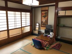 een kamer met een tafel en een kamer met ramen bij Niko Ryokan in Aizuwakamatsu