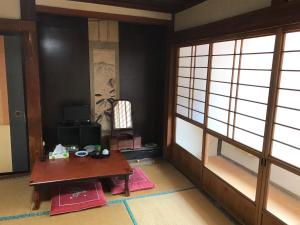 een kamer met een tafel en een kamer met ramen bij Niko Ryokan in Aizuwakamatsu