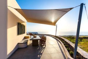 una vista dal balcone di una casa con tavolo e sedie di Villa Vinea Santorini a Imerovigli