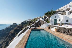 una piscina con vista sull'oceano e una casa di The Vasilicos a Imerovigli