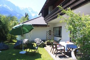 une terrasse avec une table, des chaises et un parasol dans l'établissement Landhaus Steinbrech, à Grainau