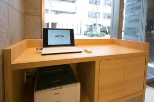 einen Laptop auf einem Schreibtisch mit Drucker in der Unterkunft Just Inn Premium Nagoya Station in Nagoya