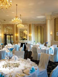 un comedor con mesas y sillas blancas y una lámpara de araña en Imperial Hotel Blackpool en Blackpool