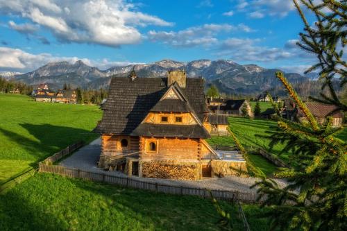 una vecchia casa in un campo con montagne sullo sfondo di Willa Giewontka a Witów