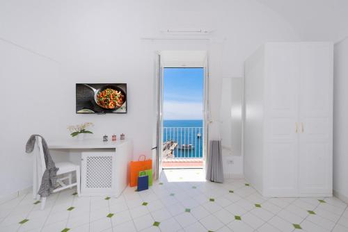 een witte kamer met een deur die uitkijkt op de oceaan bij Vista d'Amalfi in Amalfi