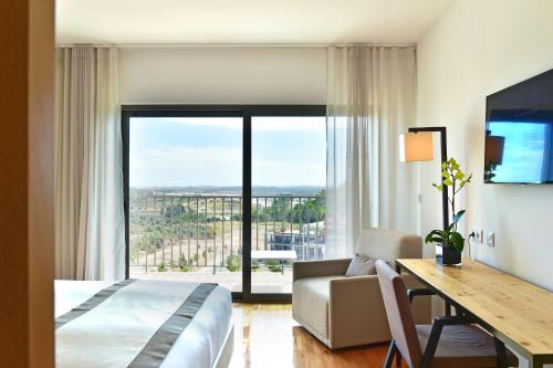 a hotel room with a bed and a desk and a window at Algarve Race Resort - Hotel in Montes de Cima