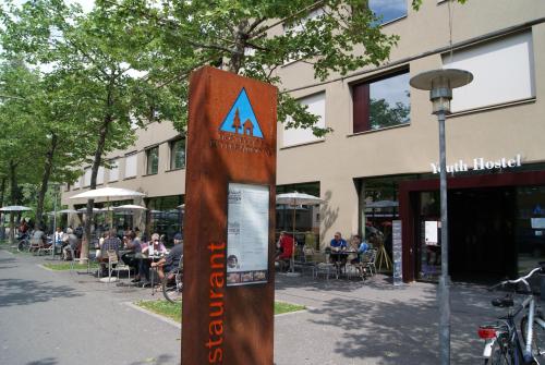 una señal frente a un edificio con gente sentada en las mesas en Interlaken Youth Hostel, en Interlaken