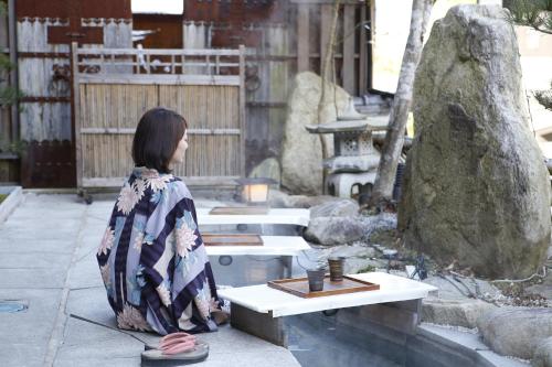 een vrouw op een bankje in een tuin bij Kikunoya in Miyajima