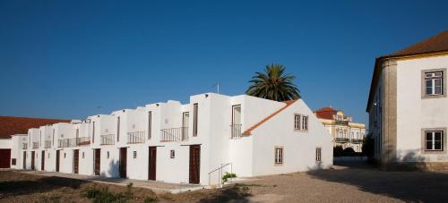 un edificio blanco con una palmera detrás en Quinta dos Álamos Agroturismo, en Golegã