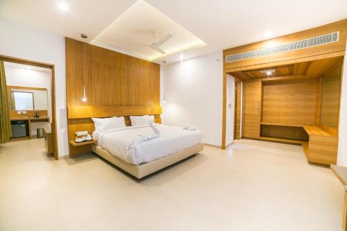 1 dormitorio con cama blanca y pared de madera en Hotel Vivera Grande, en Dindigul