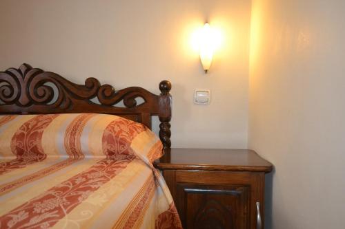 a bedroom with a bed and a nightstand with a light on the wall at Семеен Хотел Море in Sozopol