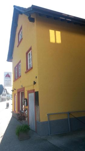 a yellow building with a red door and windows at A CÔTE in Môtiers