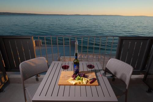 un tavolo con un piatto di cibo e una bottiglia di vino di Seaside Luxury Suites a Podstrana