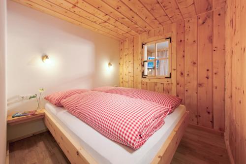 Bett in einem Zimmer mit einer Holzwand in der Unterkunft Martinshof in Sankt Johann in Tirol