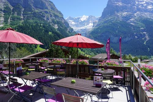 eine Terrasse mit Tischen und Stühlen mit Bergen im Hintergrund in der Unterkunft Hotel Alpenblick in Grindelwald