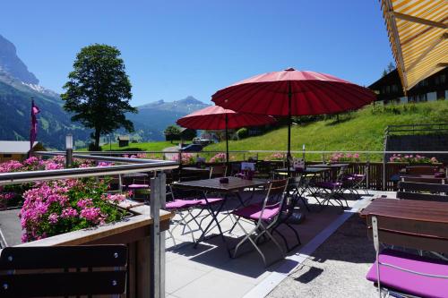 eine Terrasse mit Tischen, Stühlen und Sonnenschirmen in der Unterkunft Hotel Alpenblick in Grindelwald