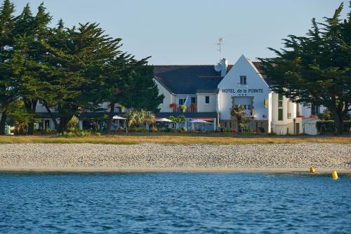 una grande casa bianca sulla riva di una spiaggia di Logis Hôtel de la Pointe du Cap Coz a Fouesnant