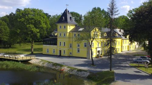 een geel huis naast een rivier met een brug bij Pałac Lucja BB in Zakrzów