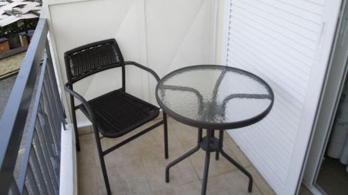 d'une table en verre et d'une chaise sur un balcon. dans l'établissement Nikolaki Rooms, à Pórto Ráfti