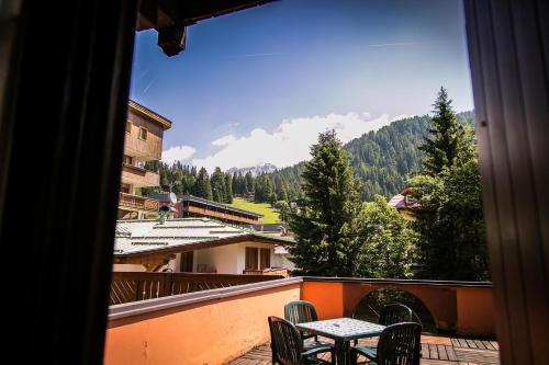 una mesa y sillas en un balcón con vistas en Hotel Posta R.T.A., en Madonna di Campiglio