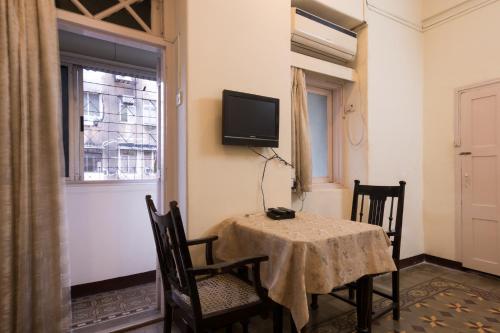 uma sala de jantar com uma mesa e uma televisão na parede em Bed and Breakfast at Colaba em Mumbai