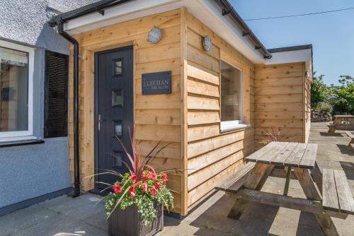 - un bâtiment en bois avec un banc et une porte dans l'établissement The Slate, à Bangor