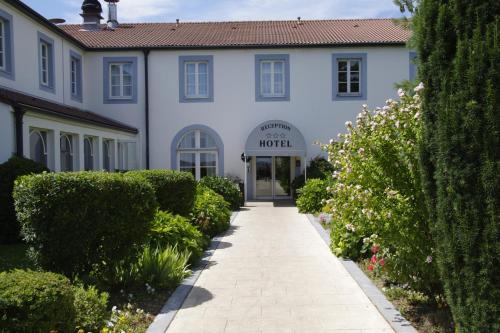 a white building with a walkway in front of it at Logis Hôtel Les Tuileries in Féy