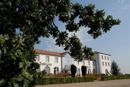 a large white building with a sign on it at Logis Hôtel Les Tuileries in Féy