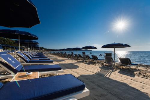 een rij ligstoelen en parasols op een strand bij Gallia Palace Hotel - Relais & Châteaux in Punta Ala