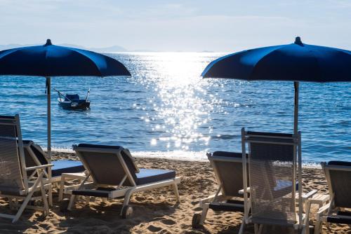 een groep stoelen en parasols op een strand bij Gallia Palace Hotel - Relais & Châteaux in Punta Ala