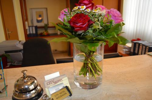 un vase de fleurs assis au-dessus d'une table dans l'établissement City Hotel Wiesbaden, à Wiesbaden