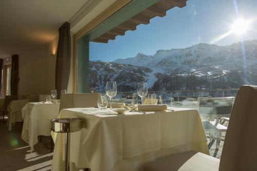 um restaurante com mesas brancas e vista para uma montanha em White Angel Hotel em Breuil-Cervinia