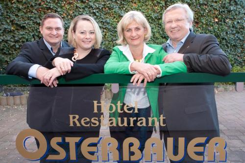 grupa trzech osób stojących za znakiem w obiekcie Hotel Restaurant Osterbauer w mieście Neunkirchen