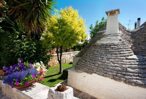 um jardim com flores e uma casa de pedra em Trullo Giardino Fiorito em Alberobello