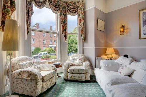 uma sala de estar com uma cama e cadeiras e uma janela em St. Aiden's Guesthouse em Rathgar