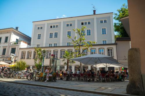 un gruppo di persone seduti ai tavoli di fronte a un edificio di Art Hotel & Hostel a Passavia