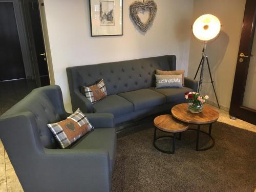 a living room with a blue couch and a table at Hotel Stadt Aurich in Aurich