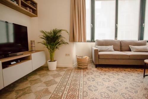 ein Wohnzimmer mit einem Sofa und einem Flachbild-TV in der Unterkunft Maison d'O in Ostende