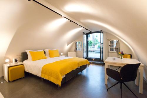 1 dormitorio con cama con almohadas amarillas y escritorio en Hotel Oudegracht, en Utrecht