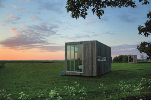 uma casa de vidro num campo com uma árvore em Hotel & Restaurant Weidumerhout em Weidum