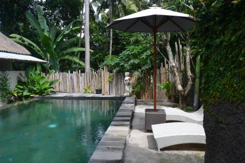 - Piscina con sombrilla, 2 sillas y mesa con sombrilla en Suka's House Bed & Breakfast, en Ubud