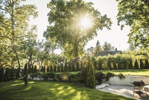 a garden with a fence and trees and the sun at Krauklis beach apartments in Saulkrasti