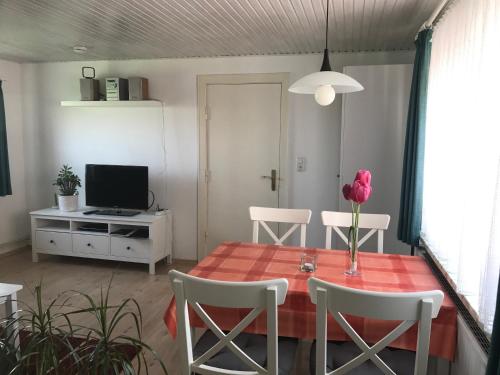 een woonkamer met een tafel en stoelen en een televisie bij Haus Heverstrom in Westerhever