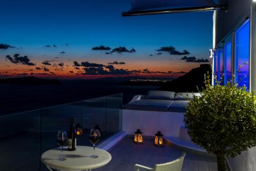 - un balcon avec vue la nuit et des verres à vin dans l'établissement Fira Deep Blue Suites, à Fira