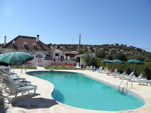 una grande piscina con sedie e ombrelloni di Hotel Jardim a Elvas