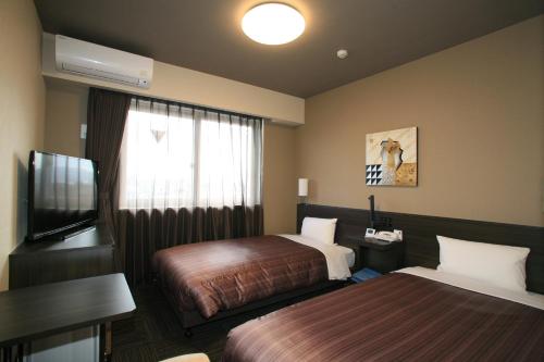 A bed or beds in a room at Hotel Route Inn Natori Iwanuma Inter Sendai Airport