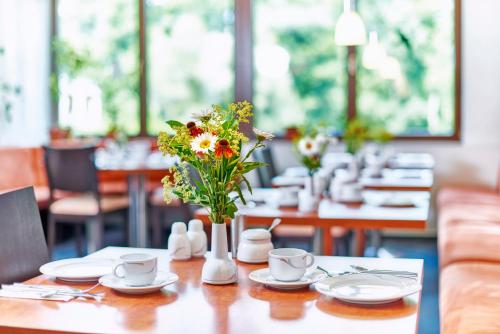 Waldhotel Sulzbachtal في Schönaich: طاولة عليها إناء من الزهور