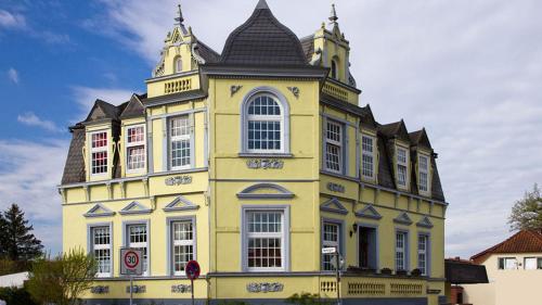 un edificio amarillo con una torre encima en Hotel Villa Schneverdingen, en Schneverdingen