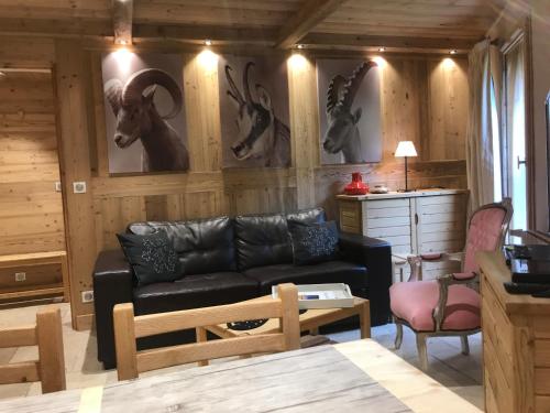 een woonkamer met een zwarte bank en dieren aan de muur bij Chalet Barmaz in Val dʼIsère