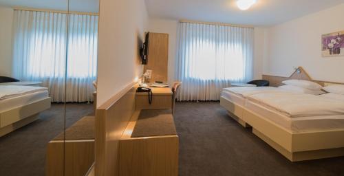 Habitación de hotel con 2 camas y espejo en Hotel am Wasen, en Freiberg am Neckar